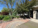 Landscaped front yard featuring mature trees and a curved paver patio - 1764 Melrose Crescent, Edmonton, AB 