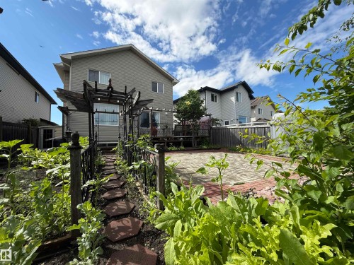 Landscaped rear yard featuring a brick paver patio, a stepping stone path, and a wooden pergola structure - 1764 Melrose Crescent, Edmonton, AB 
