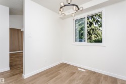 Room with light wood-finish flooring, white walls, and a modern circular chandelier - 