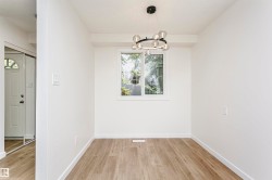 Light-filled interior space featuring a contemporary chandelier, a white-framed window, and wood-finish flooring - 