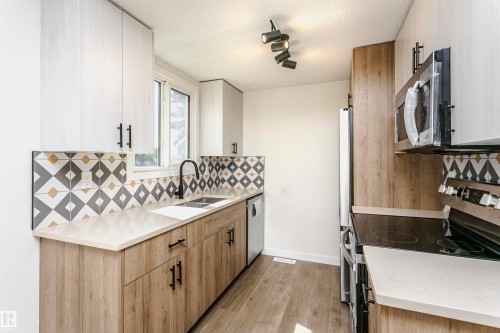 Contemporary kitchen featuring light wood-finish lower cabinetry and white upper cabinetry with black hardware - 5418 144B Avenue, Edmonton, AB 