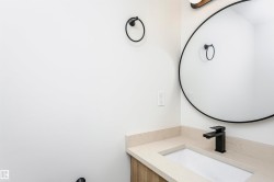 Bathroom vanity featuring a light-toned countertop, undermount sink, and matte black faucet - 
