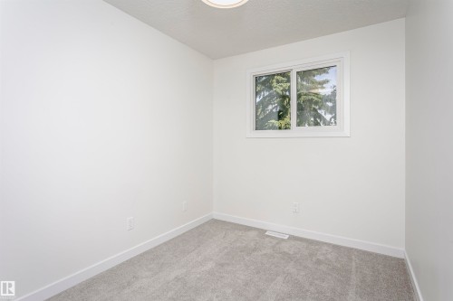 Room featuring light gray carpeting, crisp white walls, white baseboards, and a white-framed window - 5418 144B Avenue, Edmonton, AB 