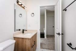 Bathroom featuring a contemporary wood-finish vanity with a light-toned countertop, an undermount sink, and a matte black faucet - 