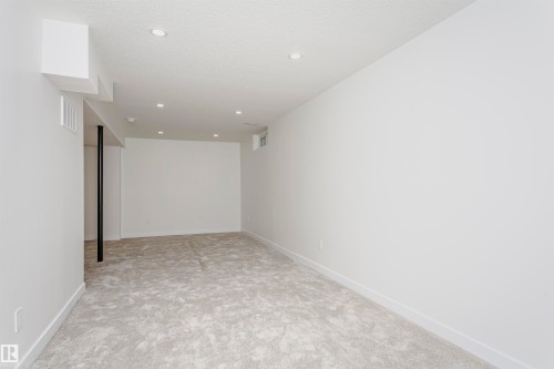 Spacious room featuring light gray carpet, white walls, recessed ceiling lighting, and white baseboards - 5418 144B Avenue, Edmonton, AB 