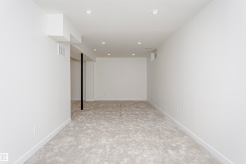 Spacious room featuring new light-toned carpeting, recessed ceiling lighting, crisp white walls, and contemporary white baseboards - 5418 144B Avenue, Edmonton, AB 
