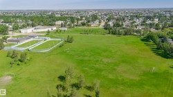 Expansive green space featuring two fenced sports courts and a large grassy field - 