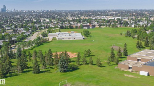 Expansive green space featuring large athletic fields, mature evergreen trees, and a distant cityscape on the horizon - 5418 144B Avenue, Edmonton, AB 