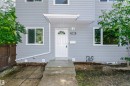 Light gray horizontal siding exterior with white trim windows and a white paneled entry door featuring an arched window detail - 5418 144B Avenue, Edmonton, AB 