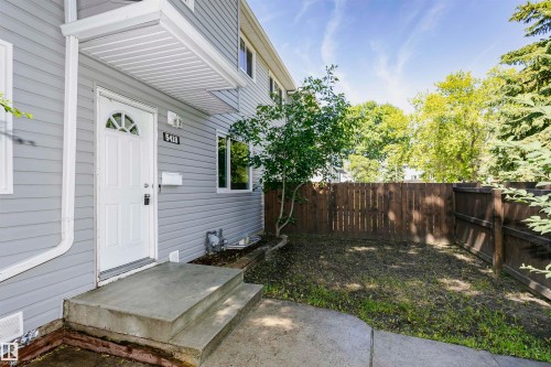 Two-story exterior with light gray siding, white front door featuring an arched window, and concrete entry steps - 5418 144B Avenue, Edmonton, AB 