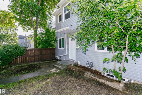 Gray siding exterior with white trim windows and a white entry door - 5418 144B Avenue, Edmonton, AB 