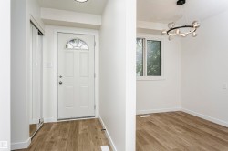 Bright entryway featuring a white paneled door with an arched transom window, wood-finish flooring, and a mirrored sliding closet door - 