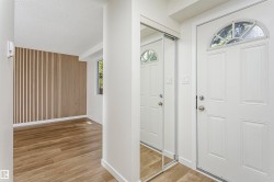 Entryway featuring a white paneled door with an arched transom window, mirrored sliding closet doors, and wood-finish flooring - 