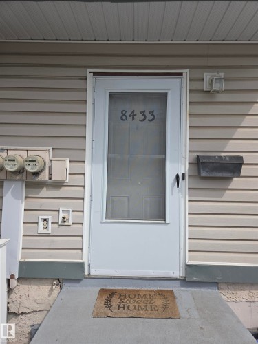Entryway featuring a storm door with numerical addressing, an exterior wall light, and a black mailbox - 8433 29 Avenue, Edmonton, AB - Outdoor With Exterior