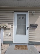 Entryway featuring a storm door with numerical addressing, an exterior wall light, and a black mailbox - 