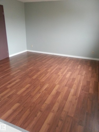 Wood-finish flooring throughout, complemented by light-toned wall paint and white baseboards - 8433 29 Avenue, Edmonton, AB - Indoor Photo Showing Other Room