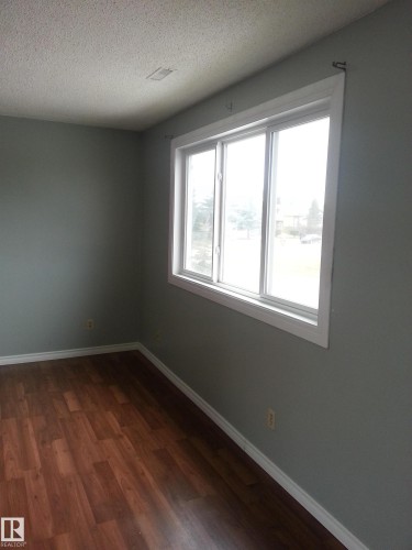 Room featuring wood-finish flooring, light gray walls, a white trim package, and a multi-pane window - 8433 29 Avenue, Edmonton, AB - Indoor Photo Showing Other Room
