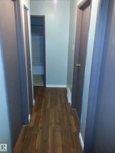 Hallway featuring wood-finish flooring, light gray walls, dark gray trim, and white baseboards - 8433 29 Avenue, Edmonton, AB - Indoor Photo Showing Other Room