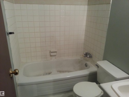 Bathtub with white subway tile surround and integrated soap dish - 8433 29 Avenue, Edmonton, AB - Indoor Photo Showing Bathroom