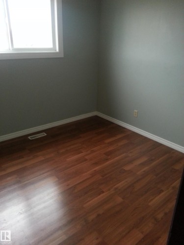 Room featuring wood-finish flooring, light gray wall paint, and crisp white baseboards - 8433 29 Avenue, Edmonton, AB - Indoor Photo Showing Other Room