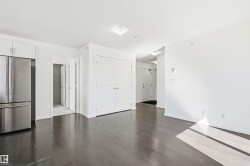 Expansive open-concept living area featuring dark wood-finish flooring and bright white walls - 