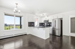 Open-concept kitchen and dining area featuring dark wood-finish flooring, white cabinetry, stainless steel appliances, and a central island with a sink - 