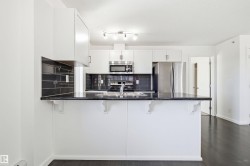 Modern kitchen featuring white cabinetry, dark stone countertops, and a black subway tile backsplash - 