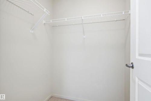 Walk-in closet featuring wire shelving, integrated hanging rods, and light-toned wall paint - 435 5515 7 Avenue, Edmonton, AB 