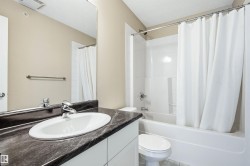Bathroom featuring a dark-toned countertop with an integrated white sink, chrome faucet, and a large wall-mounted mirror - 