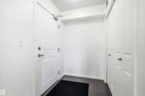 Entryway featuring dark wood-finish flooring, white walls, and a white paneled door with brushed nickel hardware - 435 5515 7 Avenue, Edmonton, AB 