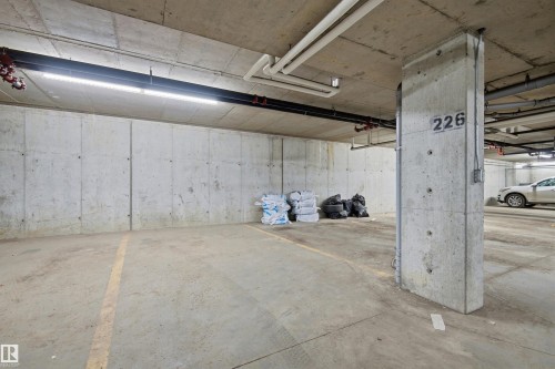 Dedicated parking stall 226 featuring concrete walls and ceiling, overhead lighting, and visible utility conduits - 435 5515 7 Avenue, Edmonton, AB 