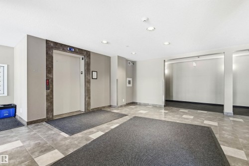Entrance lobby featuring a centered elevator with stone-look surround, recessed lighting, and tile flooring - 435 5515 7 Avenue, Edmonton, AB 