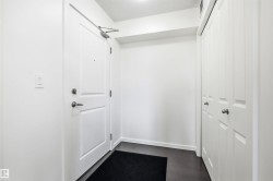 Entryway featuring dark wood-finish flooring, white walls, and a white paneled door with brushed nickel hardware - 