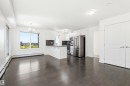 Open-concept living space featuring wood-finish flooring and a bright kitchen with stainless steel appliances - 435 5515 7 Avenue, Edmonton, AB 