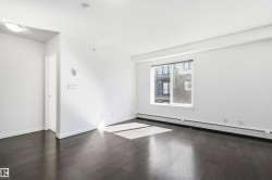 Spacious room featuring dark wood-finish flooring, white walls, and a large window with white trim - 