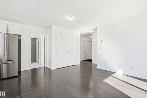 Expansive open-concept living area featuring dark wood-finish flooring and bright white walls - 435 5515 7 Avenue, Edmonton, AB 