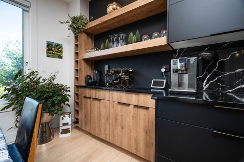 Custom built-in cabinetry with wood-finish doors and open shelving, featuring black countertops and a matching black backsplash with white veining - 4714 Charles Bay Bay, Edmonton, AB 