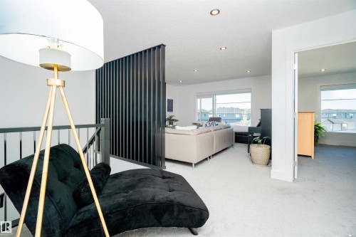 Upper-level landing featuring a dark slatted room divider, carpeted flooring, recessed lighting, and a metal railing - 4714 Charles Bay Bay, Edmonton, AB 
