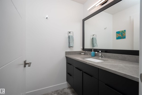 Modern bathroom vanity featuring a rectangular undermount sink, a gray countertop with white veining, and matte black cabinetry with integrated pulls - 4714 Charles Bay Bay, Edmonton, AB 