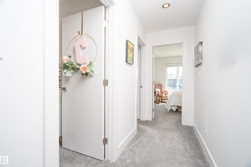 Hallway featuring light gray carpeting, white baseboards, and bright white walls - 4714 Charles Bay Bay, Edmonton, AB 
