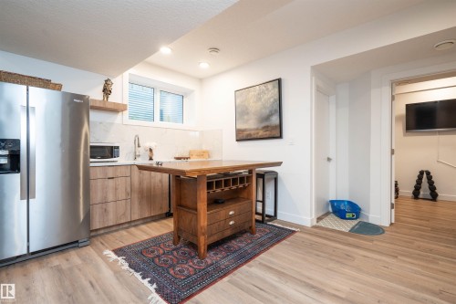 Compact kitchen area featuring wood-finish cabinetry, stainless steel appliances, and a solid surface countertop - 4714 Charles Bay Bay, Edmonton, AB 