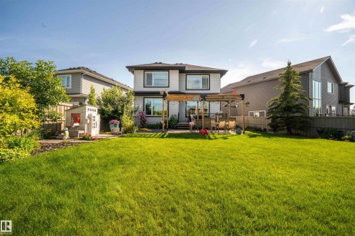 Expansive green lawn with a two-story residence featuring a ground-level patio, pergola, and fenced perimeter - 4714 Charles Bay Bay, Edmonton, AB 