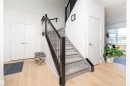 Entryway featuring wood-finish flooring, a carpeted staircase with a dark banister, white walls, and recessed lighting - 4714 Charles Bay Bay, Edmonton, AB 