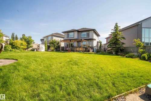 Spacious rear yard featuring an expansive lawn, a two-story residence with a back deck, and mature landscaping elements - 4714 Charles Bay Bay, Edmonton, AB 