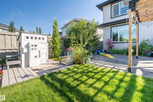 Expansive backyard featuring a manicured lawn, concrete patio, and a light wood pergola - 4714 Charles Bay Bay, Edmonton, AB 