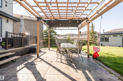 Expansive concrete patio with a wooden pergola, equipped with string lighting and a central shade cover - 4714 Charles Bay Bay, Edmonton, AB 