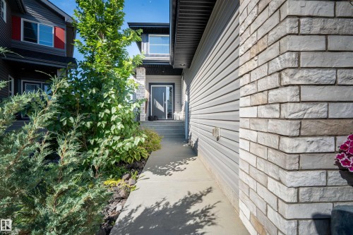 Stone and siding exterior with a concrete walkway leading to the front entry - 4714 Charles Bay Bay, Edmonton, AB 