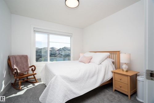 Bright bedroom featuring a large window, plush gray carpeting, white walls, a flush-mount ceiling light, and white trim - 4714 Charles Bay Bay, Edmonton, AB 