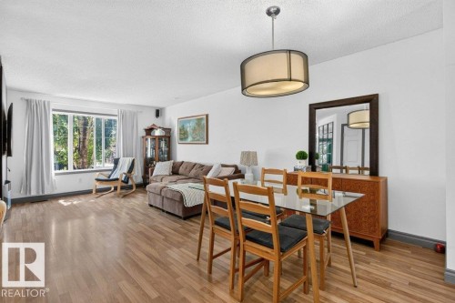 Open-concept living and dining area featuring wood-finish flooring, white walls, and a large window - 21320 90 Avenue, Edmonton, AB 