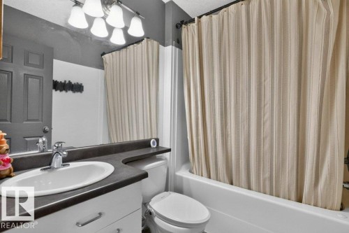 Bathroom featuring a vanity with a white oval sink, dark countertop, and brushed nickel faucet - 21320 90 Avenue, Edmonton, AB 